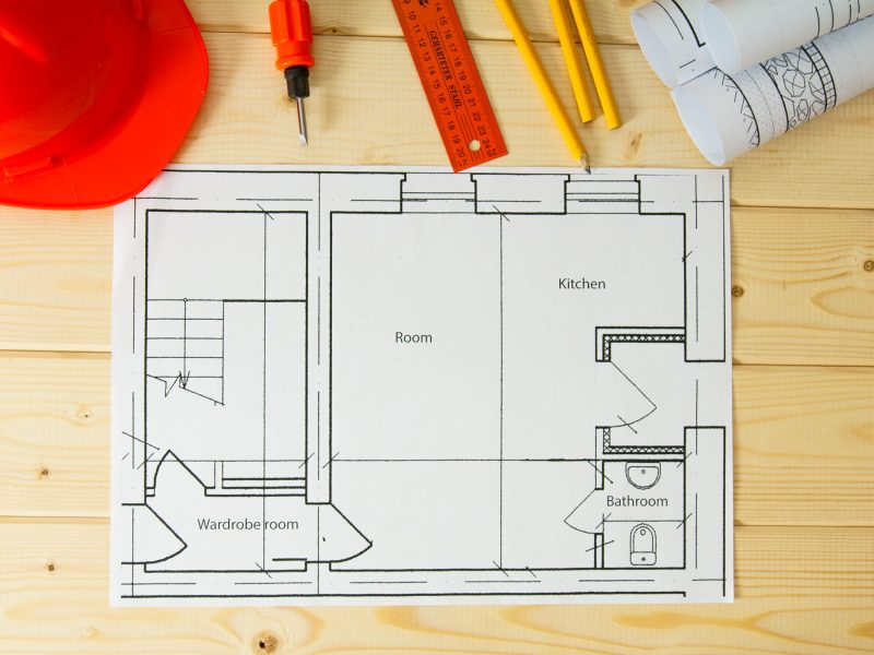Planning of repair of apartment. Repair work. Drawings for building, helmet, pencils on wooden background.